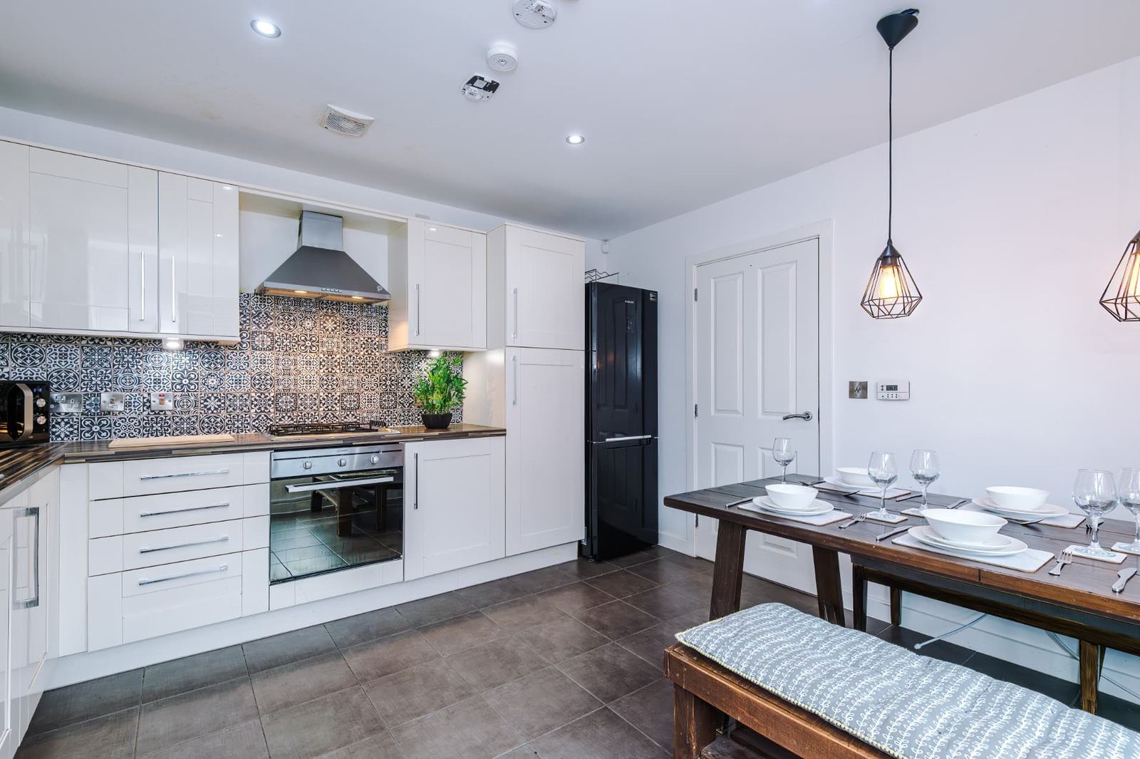 Fitted kitchen with a patterned tiled splashback and a laid dining table