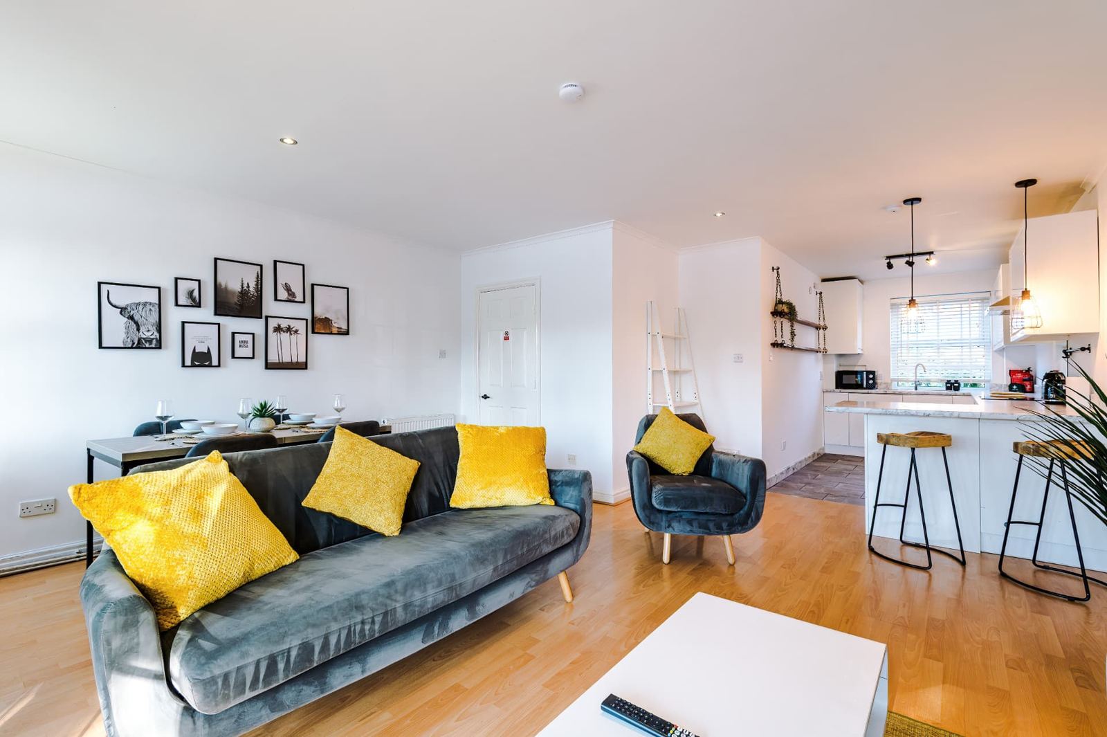 Furnished open-plan living and dining area with a kitchen beyond, prepared for short-stay guests
